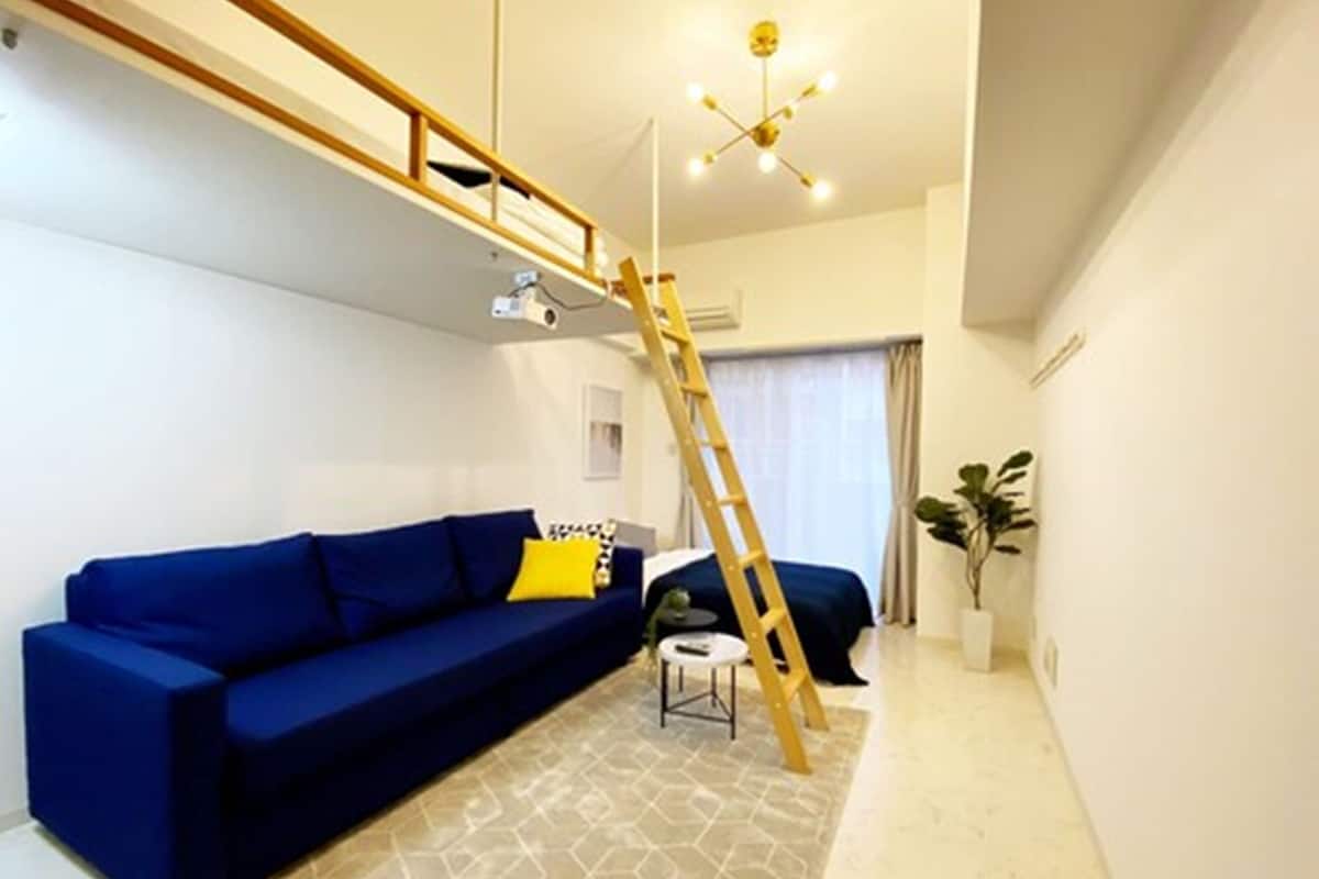 Ein modernes Wohnzimmer mit einem blauen Sofa, einer Holzleiter und einem Teppich mit geometrischem Muster.