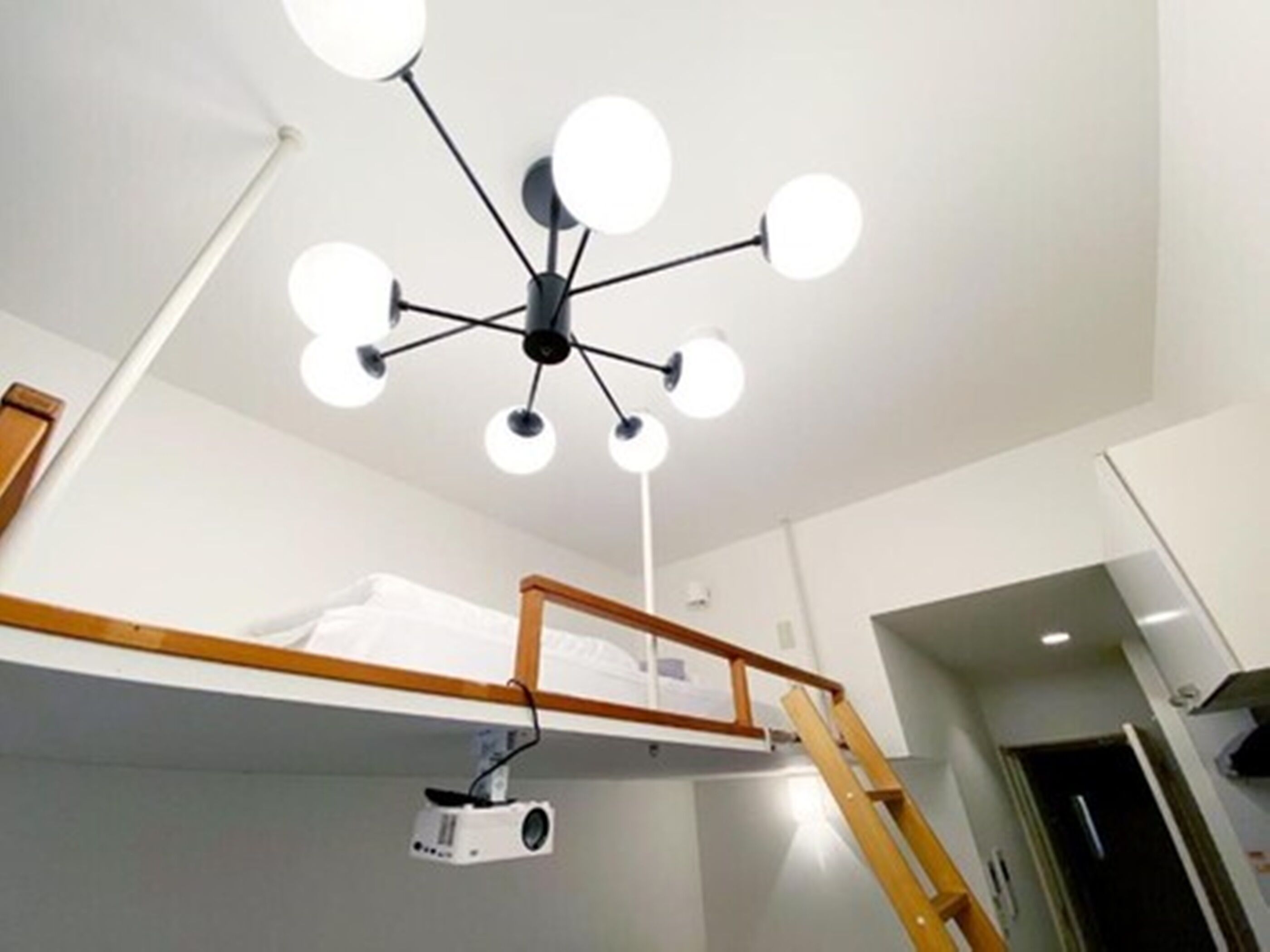 A bunk bed with a projector mounted on the wall and a ceiling light fixture.