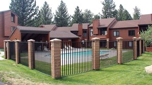 A residential complex with multiple brick houses, a swimming pool, and a gated entrance.