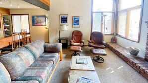 A living room with a sofa, two leather chairs, a coffee table, and a fireplace.