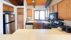 A kitchen with wooden cabinets, a stainless steel refrigerator, a dishwasher, a stove, and a microwave.