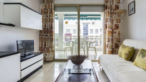A modern living room with a sofa, a coffee table, and a TV on a cabinet. - Turquesa by Interhome (La Pineda)