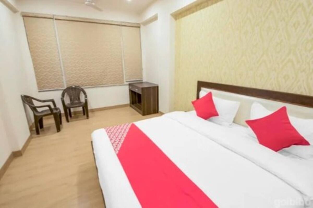 Una habitación de hotel con una cama, dos sillas, un escritorio y una ventana con persianas.