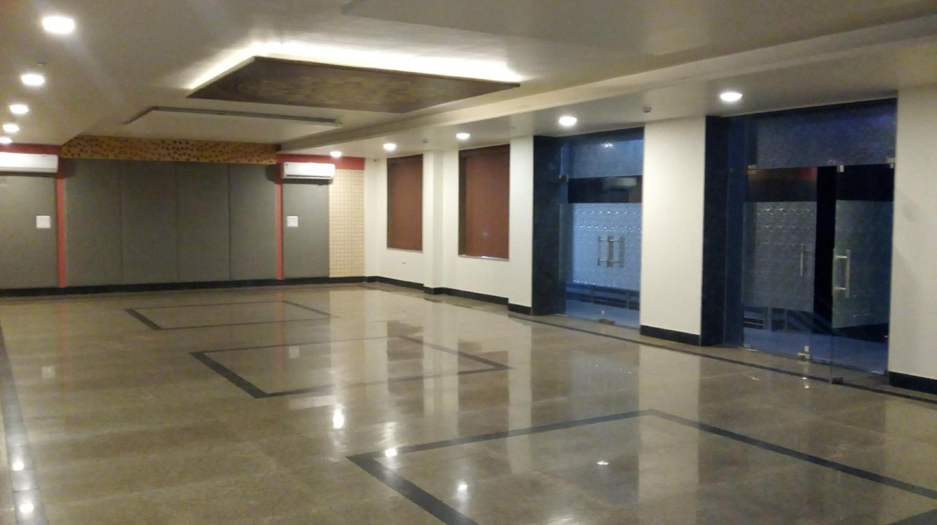 A spacious corridor with a polished floor, recessed lighting, and doors leading to rooms.