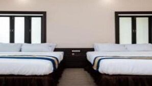 A hotel room with two beds, a dark headboard, and a small bedside table. - Gulabi Bagh Resort (A unit of Sarvmangla Garden) (Jaipur)