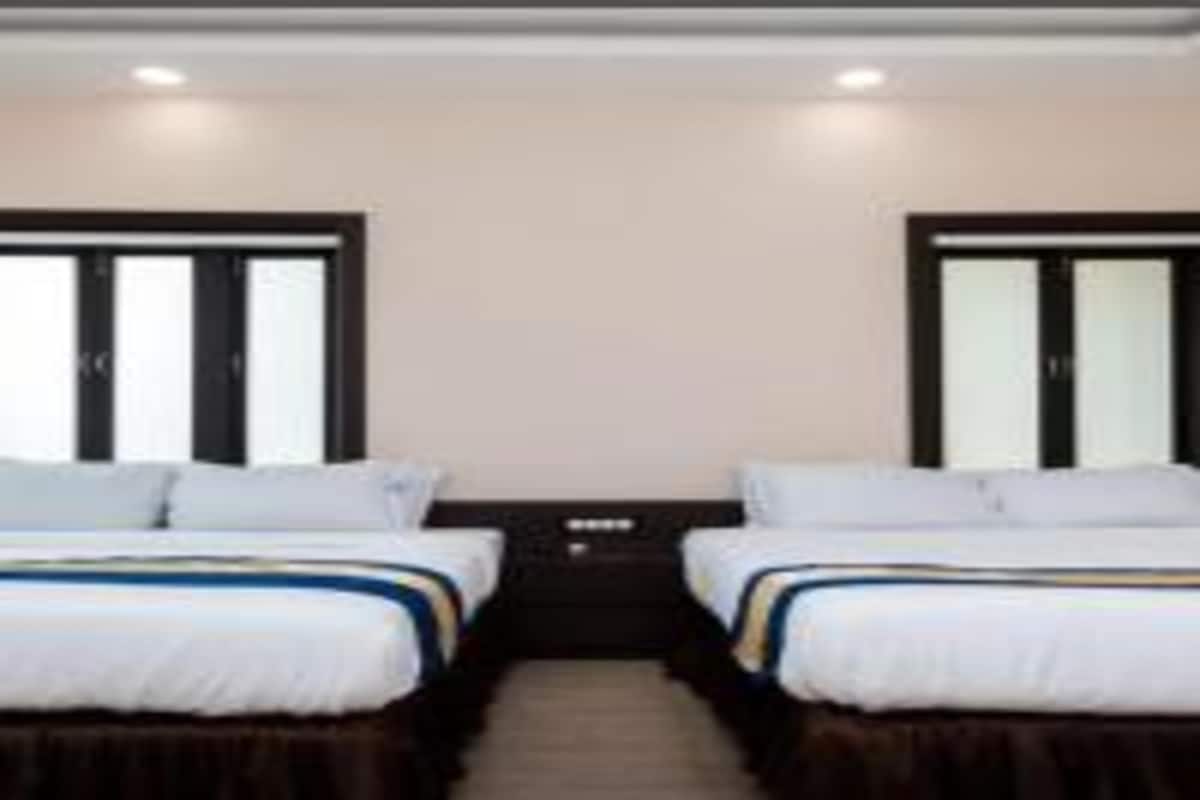 Una habitación de hotel con dos camas, un cabecero oscuro y una mesita de noche pequeña.