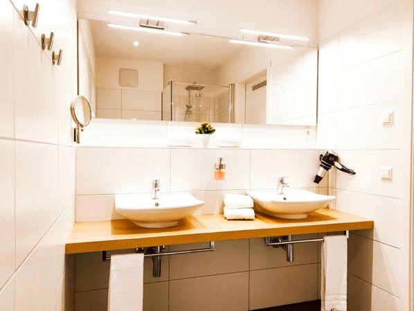 Un baño moderno con dos lavamanos, un espejo grande y un perchero para toallas.