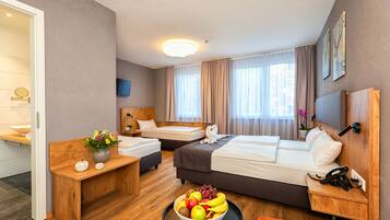 Hotelkamer met twee bedden, een houten bureau, een schaal fruit en een badkamer zichtbaar door een geopende deur.