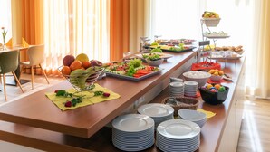 Una mesa de buffet con diversos alimentos y una pila de platos blancos.