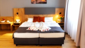 Habitación de hotel con una cama grande, dos mesitas de noche, un cuadro en la pared y una ventana con cortinas.