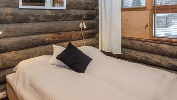 A log cabin bedroom with a bed, a hanging light, and a window with blinds.