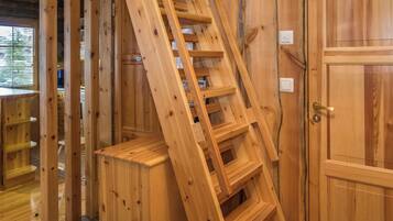 A wooden interior with a wooden staircase, a door, and a window with blinds.