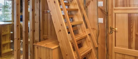 Un intérieur en bois avec un escalier en bois, une porte et une fenêtre avec des stores.