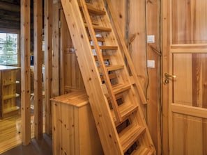 Un interior de madera con una escalera de madera, una puerta y una ventana con persianas.