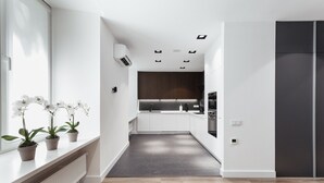 A modern kitchen with white cabinets, a dark countertop, and a built-in oven. - Royal Apartment Primorskiy bulvar 1 (Odesa)