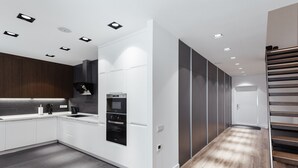 A modern kitchen with white cabinetry, a built-in oven, and a stainless steel range hood. - Royal Apartment Primorskiy bulvar 1 (Odesa)