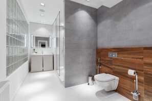 A modern bathroom with a glass shower enclosure, a wooden vanity, and a white toilet.
