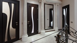 A hallway with black-framed doors, white columns, and a large mirror. - Royal Apartment Uspenskaya 12 (Odesa)