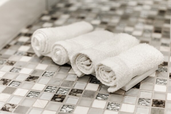 Three rolled white towels on a tiled floor with a mosaic pattern. - Royal Apartments Gagarinskoe plato 5a (Odesa)