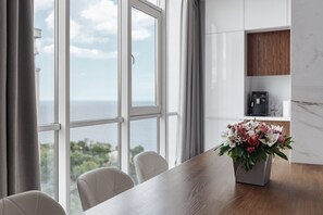 Enjoy meals in this dining area with a view, featuring a table and chairs, a floral arrangement, and a kitchen area with a coffee machine.