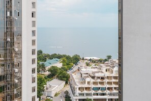 Un immeuble de grande hauteur offrant une vue sur une zone côtière, notamment sur un port de plaisance et des immeubles résidentiels.