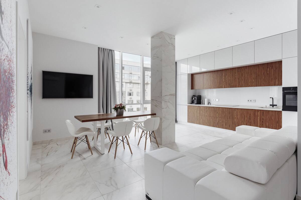 Una cocina moderna con armarios blancos, una encimera de madera y un horno empotrado.