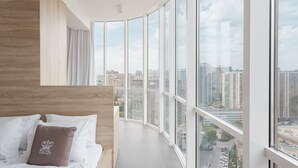 Une chambre à coucher moderne avec une grande fenêtre, un plafond incurvé et une vue sur le paysage urbain.