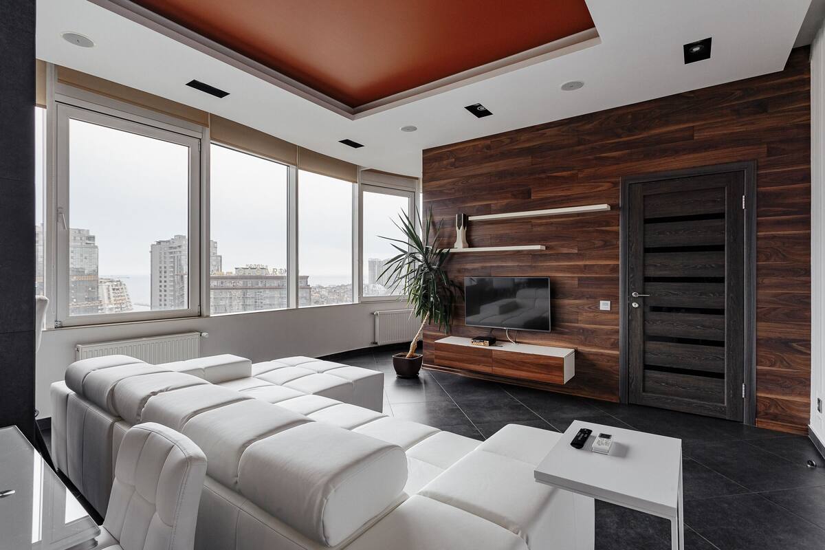 Una sala de estar moderna con un ventanal grande, un sofá, un televisor y una pared de madera.