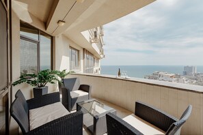 Een balkon met rieten meubilair, een glazen tafel en een bloempot.