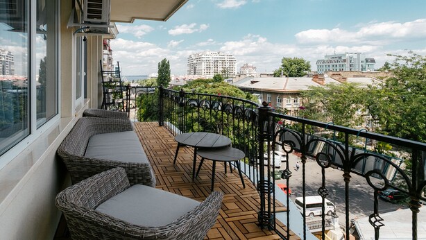 A balcony with wicker furniture and a view of the cityscape. - Royal Apartment Zhukovskogo 9 (Odesa)
