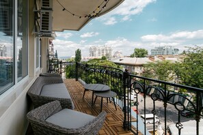 Un balcón con mobiliario de mimbre y vista panorámica de la ciudad.