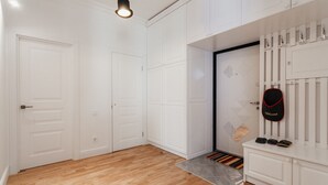 A hallway with white doors, a shoe rack with a 'Welcome' sign, and a wooden floor. - Royal Apartment Zhukovskogo 9 (Odesa)