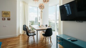 A modern dining area with a wooden table, black chairs, and a large window offering a city view. - Royal Apartment Zhukovskogo 9 (Odesa)