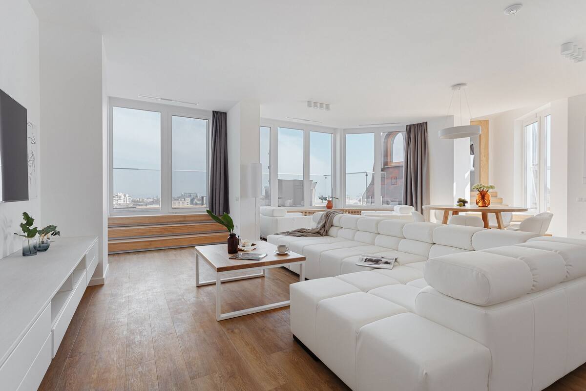 A modern living room with a white sofa, a coffee table, and a dining area with a table and chairs.