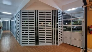 A corridor with a series of lockers and a glass door leading to a parking area.
