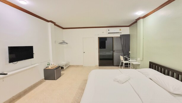 A hotel room with a bed, a desk, a chair, a television, and an air conditioning unit.