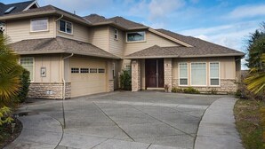 A two-story house with a garage, a driveway, and a well-maintained lawn. - Twinview executive one-bedroom suite (Victoria)
