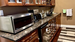 A kitchen with wooden cabinets, a microwave, a toaster, and a coffee maker. - Twinview executive one-bedroom suite (Victoria)
