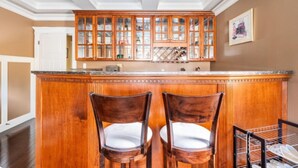 A kitchen with wooden cabinets, a central island with chairs, and a white door in the background. - Twinview executive one-bedroom suite (Victoria)