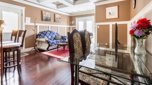 A spacious living room with a glass coffee table, a sofa, and a dining area with chairs. - Twinview executive one-bedroom suite (Victoria)