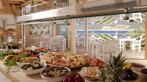 Un bufé con diferentes opciones de comida y vista al área de mesas al aire libre.