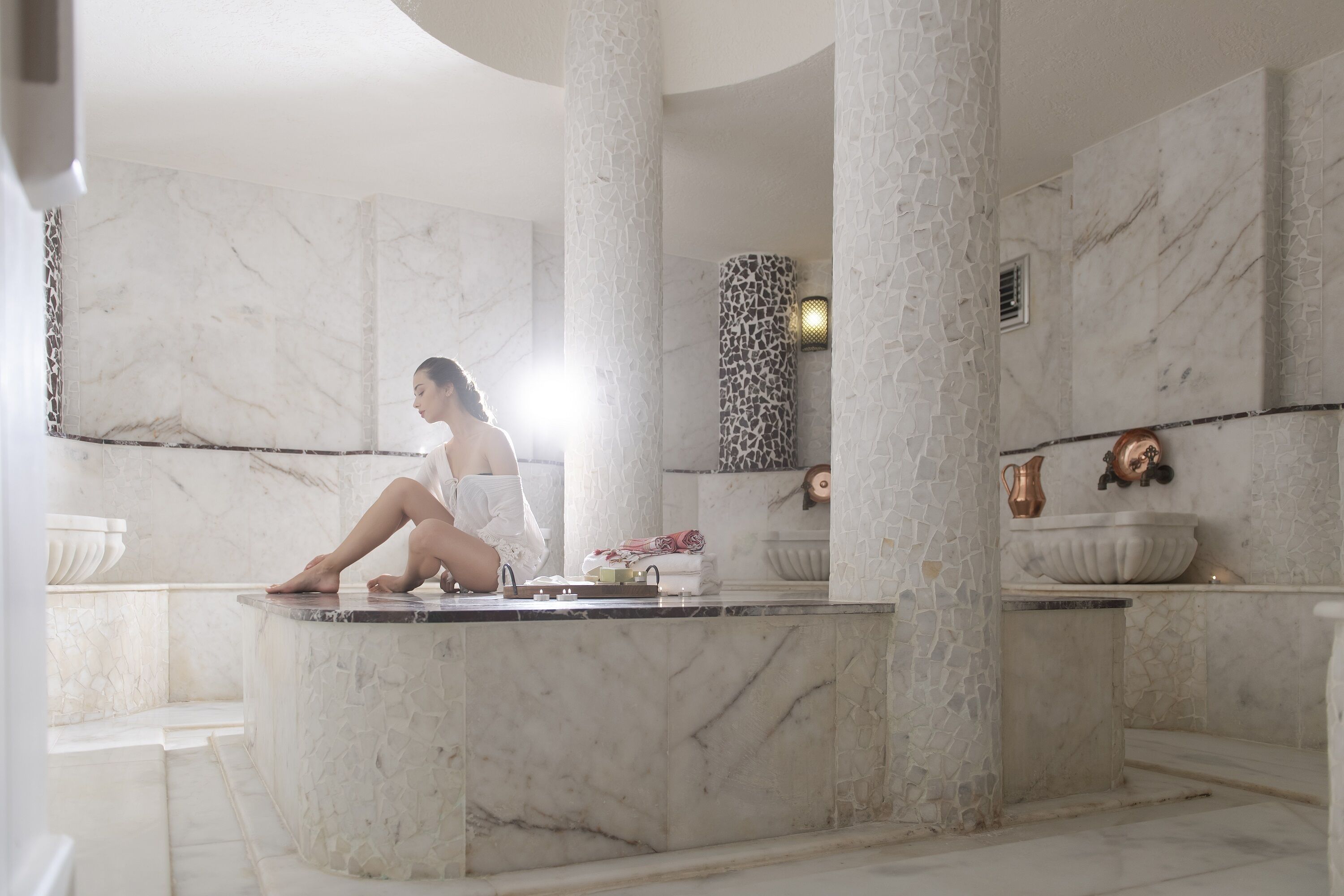 Zona de spa con columnas de mármol, bañera y elementos decorativos.