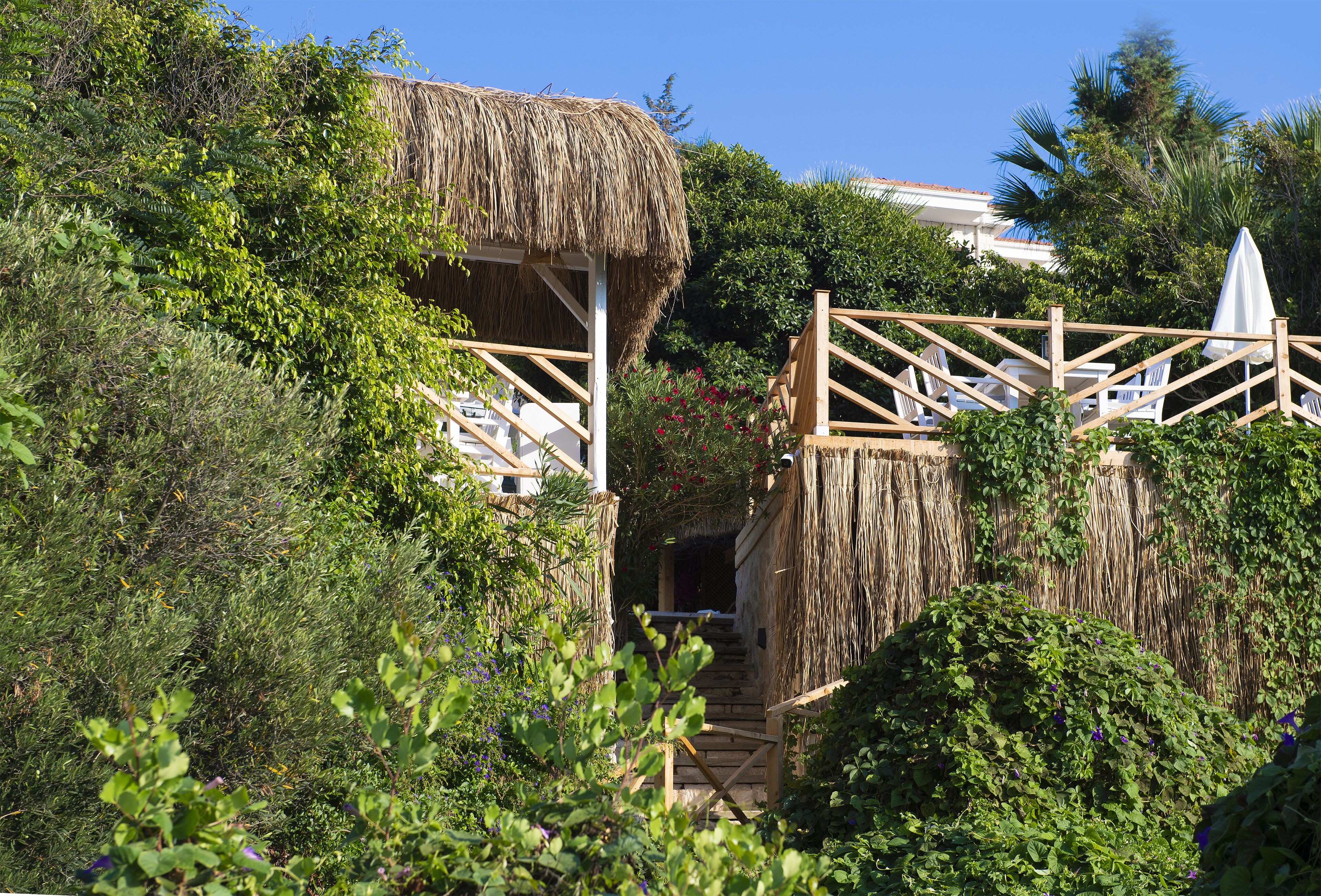 A thatched-roof structure with outdoor seating and a staircase leading to a higher level.
