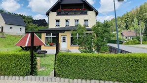 Une maison à deux étages avec un balcon, un petit jardin et un lampadaire.