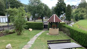 Un jardin agrémenté d’un belvédère, d’un sentier en pierre et de tables de pique-nique.