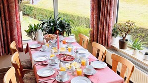 Une table à manger dressée pour le petit-déjeuner, avec vue sur un paysage rural.