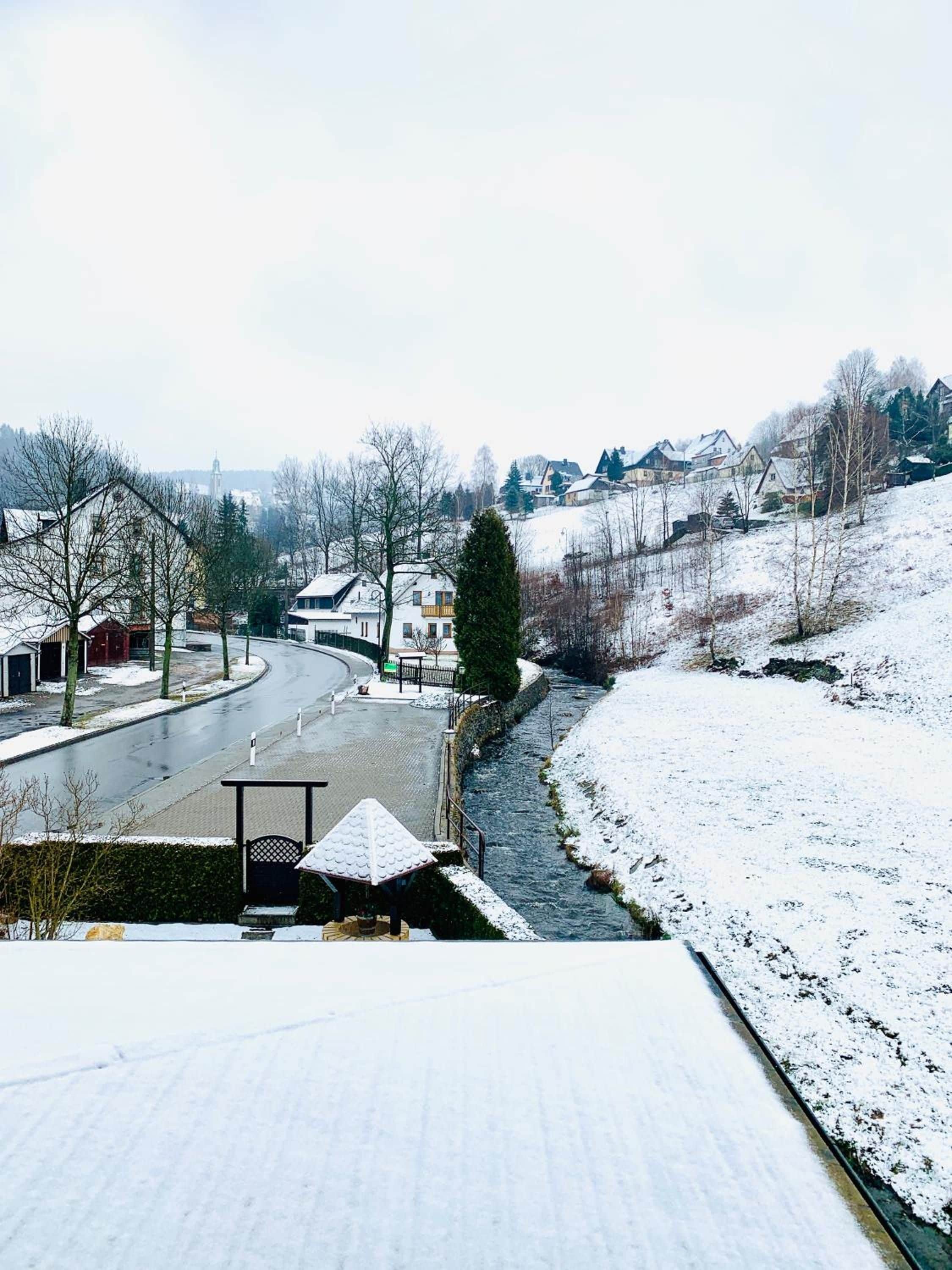 Un paysage enneigé avec une rivière, des bâtiments et un ciel dégagé.