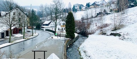 Un paysage enneigé avec une rivière, des bâtiments et un ciel dégagé.