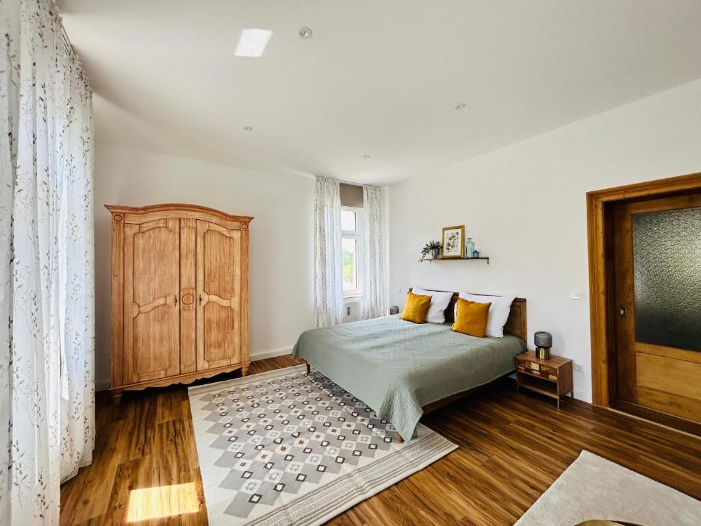 A bedroom with a bed, wooden wardrobe, and a patterned rug.