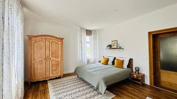 A bedroom with a bed, wooden wardrobe, and a patterned rug.